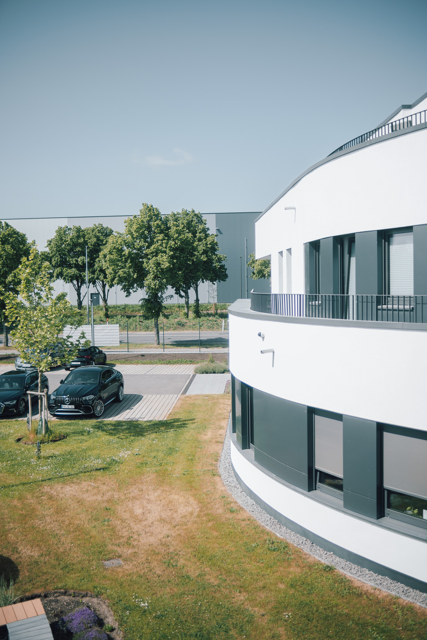 big white building with trees and cars